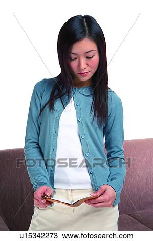 Young woman standing and looking at notebook View Large Photo Image Stock Image - Young woman standing and looking at notebook. Fotosearch