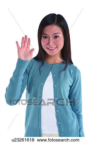 Stock Photo - Young woman standing, hand raised. Fotosearch