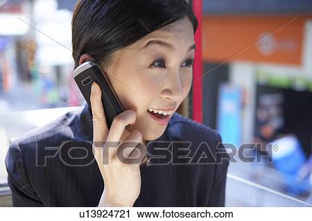 Stock Image - Young Businesswoman Riding Tram and using mobile phone, Smiling. Fotosearch