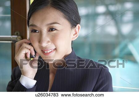 Stock Image - Young Businesswoman Riding Tram and using mobile phone, Smiling. Fotosearch