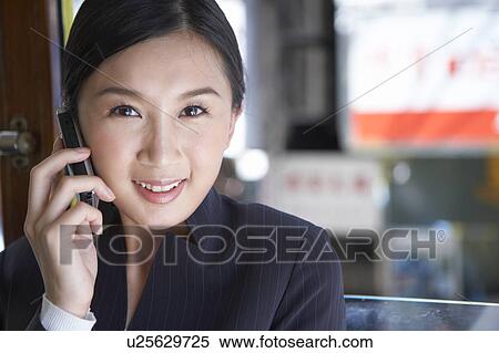 Stock Photography - Young Businesswoman Riding Tram and using mobile phone, Smiling. Fotosearch