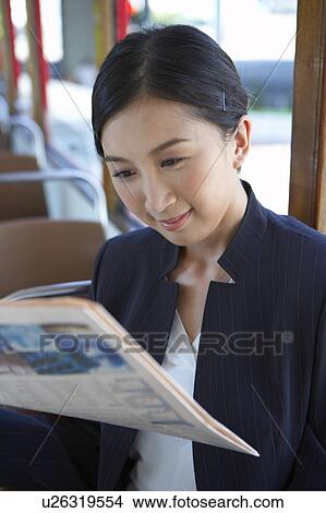 Picture - Young Businesswoman Riding Tram, Reading Newspaper. Fotosearch