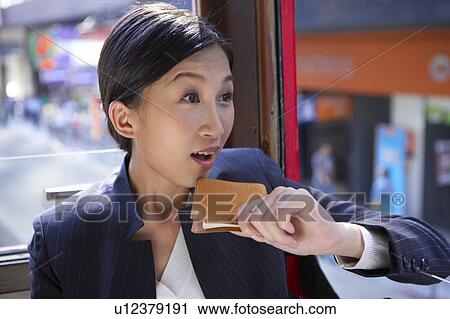 Stock Image - Young Businesswoman Riding Tram, Holding a Diary, Looking Away. Fotosearch