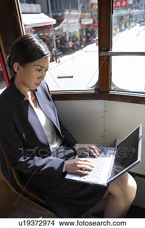 Picture - Young Businesswoman Riding Tram using Laptop. Fotosearch