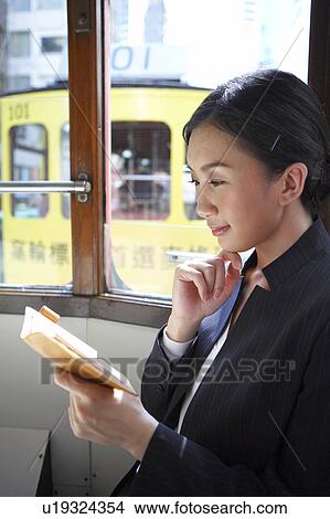Picture - Young Businesswoman Riding Tram with Diary. Fotosearch