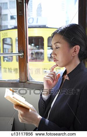 Stock Photograph - Young Businesswoman Riding Tram with Diary. Fotosearch