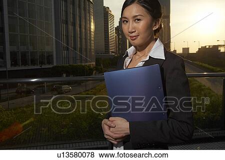 Young Businesswoman Standing in Street, Holding File, Smiling View Large Photo Image Stock Photo - Young Businesswoman Standing in Street, Holding File, Smiling. Fotosearch