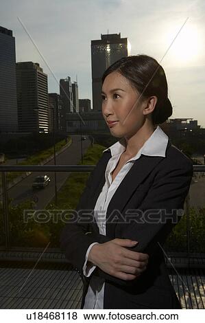 Stock Photo - Young Businesswoman Standing in Street, Looking Away. Fotosearch
