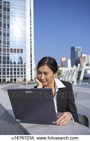 Picture - Young Businesswoman using Laptop Outdoor. Fotosearch