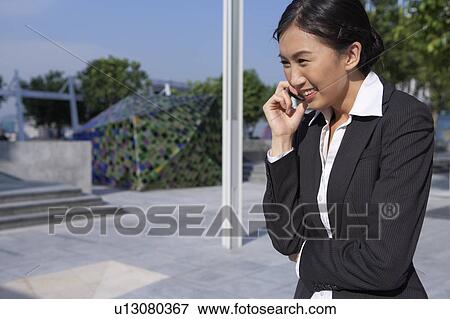 Stock Photo - Young Businesswoman using mobile phone, Smiling. Fotosearch