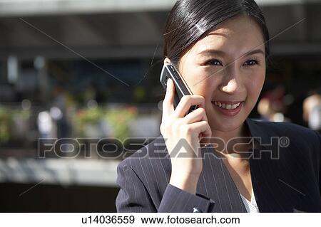 Stock Photo - Young Businesswoman Using Mobile Phone in Street, Smiling. Fotosearch