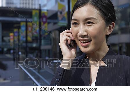 Stock Photograph - Young Businesswoman using mobile phone, Smiling. Fotosearch