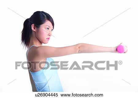 Stock Photography - Young woman holding dumbbell, side view. Fotosearch