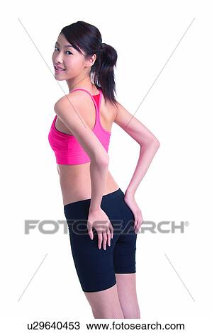 Stock Image - Young woman in sporty wear, standing, three quarter length. Fotosearch