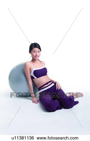 Young woman leaning on a big ball, full length View Large Photo Image Stock Photograph - Young woman leaning on a big ball, full length. Fotosearch