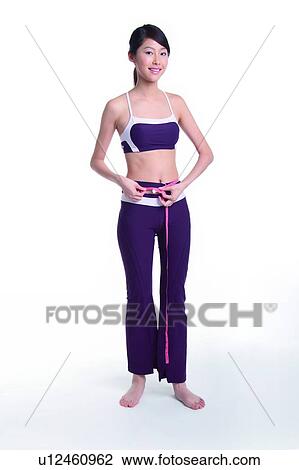 Stock Image - Young woman measuring, full length. Fotosearch