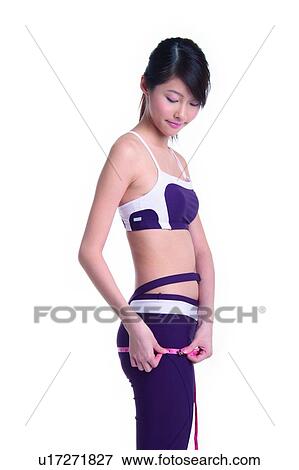 Stock Photo - Young woman measuring, three quarter length. Fotosearch