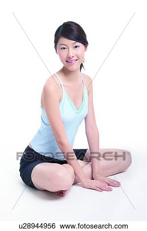 Stock Photograph - Young woman sitting, hands on floor, leaning forwards. Fotosearch