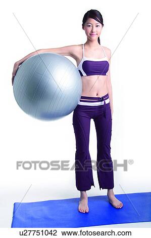 Young woman standing and holding a big ball View Large Photo Image Stock Image - Young woman standing and holding a big ball. Fotosearch
