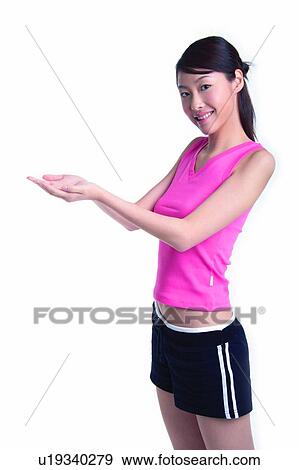 Stock Photo - Young woman standing, holding somethings, side view. Fotosearch