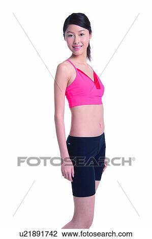 Stock Image - Young woman standing in side view. Fotosearch
