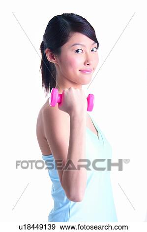 Stock Photo - Young woman wearing tank top and lifting dumbbell. Fotosearch