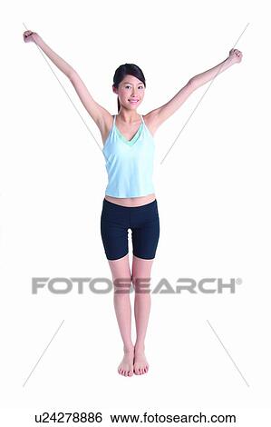 Stock Photograph - Young woman wearing tank top and raising hands. Fotosearch