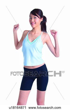 Stock Image - Young woman wearing tank top with arms raised. Fotosearch