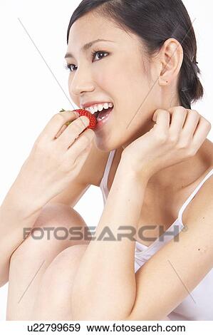 Stock Photo - Portrait of Natural Young girl eating Strawberry. Fotosearch