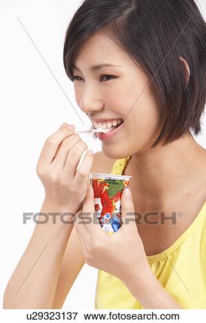 Stock Photo - Portrait of Natural Young girl Eating Yoghurt, Close-Up, Portrait. Fotosearch
