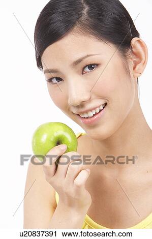 Stock Image - Portrait of Natural Young girl holding Apple, Smiling. Fotosearch