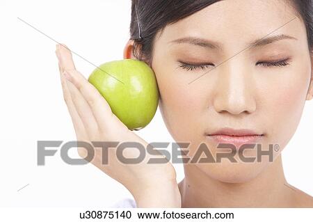 Stock Image - Portrait of Natural Young girl Holding Apple, Eyes Closed. Fotosearch