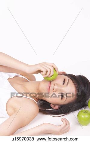 Stock Photo - Portrait of Natural Young girl lying on Floor, Holding Apple. Fotosearch