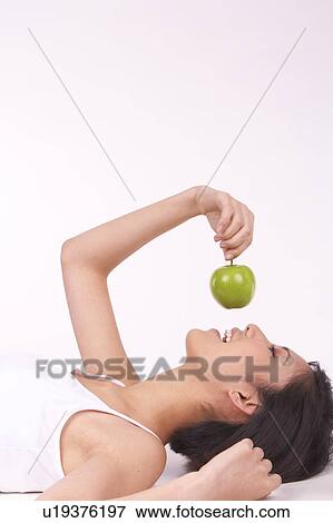 Portrait of Natural Young girl lying on Floor, Holding Apple View Large Photo Image Stock Photo - Portrait of Natural Young girl lying on Floor, Holding Apple. Fotosearch