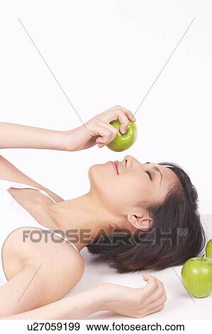 Portrait of Natural Young girl lying on Floor, Holding Apple View Large Photo Image Stock Photo - Portrait of Natural Young girl lying on Floor, Holding Apple. Fotosearch