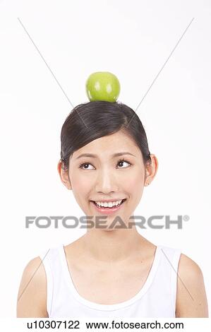 Stock Image - Portrait of Natural Young girl with an Apple on Her Head, Smiling. Fotosearch