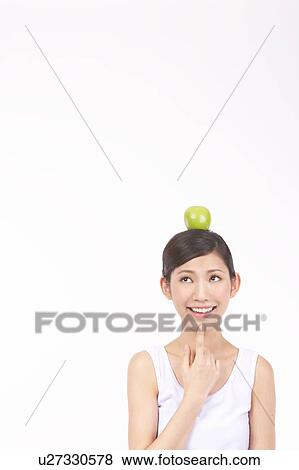 Stock Photo - Portrait of Natural Young girl with an Apple on Her Head. Fotosearch