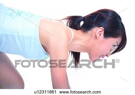 Stock Image - Young woman bending forward in a ready to run pose. Fotosearch