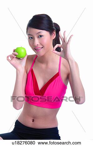 Young woman holding green apple and making OK sign View Large Photo Image Stock Image - Young woman holding green apple and making OK sign. Fotosearch
