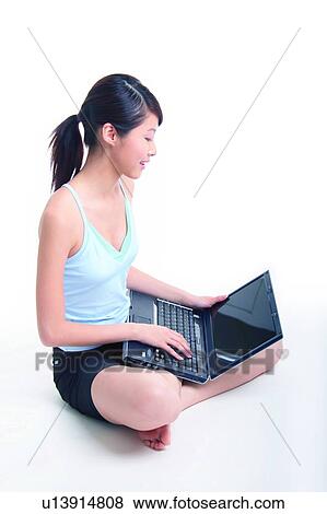 Young woman sitting and using notebook, crossed-legged View Large Photo Image Stock Photo - Young woman sitting and using notebook, crossed-legged. Fotosearch