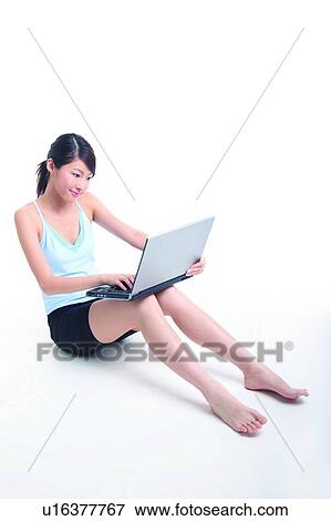 Young woman sitting and using notebook View Large Photo Image Stock Photo - Young woman sitting and using notebook. Fotosearch
