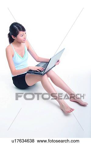 Stock Photo - Young woman sitting and using notebook. Fotosearch