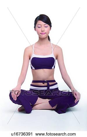 Stock Image - Young woman sitting cross-legged, eyes closed. Fotosearch