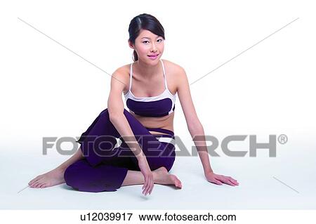 Stock Photo - Young woman sitting on floor, looking at camera. Fotosearch