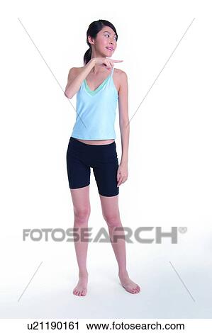 Stock Image - Young woman standing and pointing to right. Fotosearch