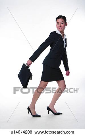 Stock Photo - Young woman in business suit, carrying briefcase, rushing in hurry. Fotosearch