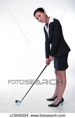 Young woman in business suit, holding golf club, looking at front, full length, side view View Large Photo Image Picture - Young woman in business suit, holding golf club, looking at front, full length, side view. Fotosearch