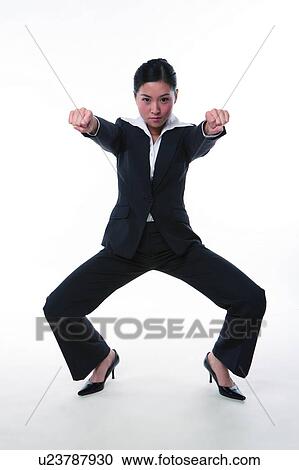 Stock Image - Young woman in business suit, in kung fu stance. Fotosearch