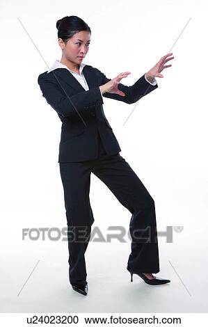 Stock Image - Young woman in business suit, in kung fu pose. Fotosearch