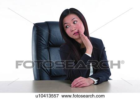 Young woman in business suit, sitting on armchair in a posture of talking secret View Large Photo Image Stock Photo - Young woman in business suit, sitting on armchair in a posture of talking secret. Fotosearch